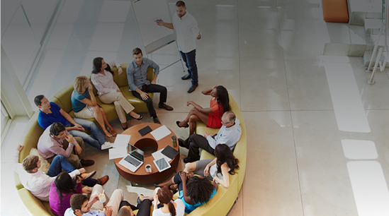A team of people sitting around a circular sofa.