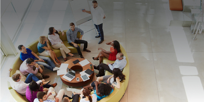 Photograph of a group of people meeting on a circular sofa.