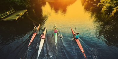 Overhead photograph of a group of four crew boats rowing at dawn.