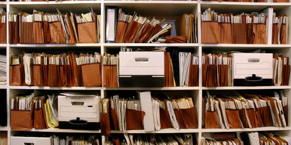 Photograph of a set of shelves containing boxes and expanding folders of legal files.