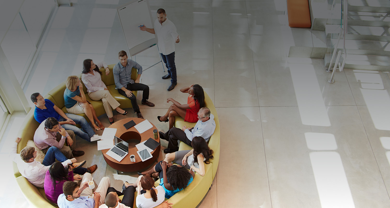 A team of people sitting around a circular sofa.